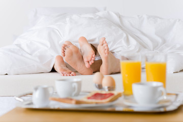 Fototapeta na wymiar Luxury hotel honeymoon breakfast - couple in bed