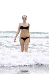 Young woman standing on a beach and enjoying the sun