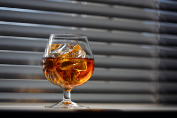 Whisky glass with ice on a window sill