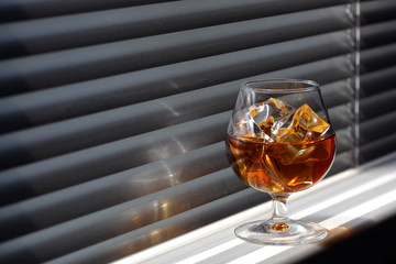 Whisky glass with ice on a window sill