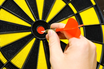 Male hand throwing dart arrow in bulls eye on dart board game