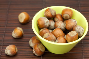 hazelnuts in a bowl on a bamboo mat