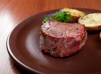 Grilled beef on white plate with potatoes