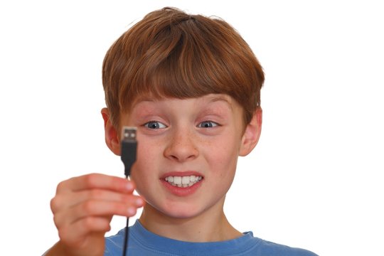 Verwirrter Junge schaut auf einen USB-Stecker