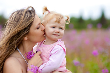 Mother kissing daughter in meadow outdoor