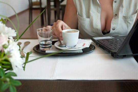 Woman with cup of espresso and laptop