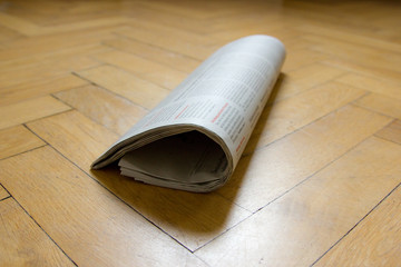 Zeitung Newspaper auf Holzboden Parkett halb gerollt
