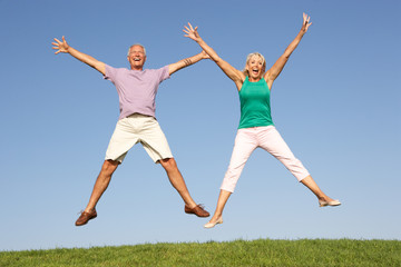 Fototapeta na wymiar Senior couple jumping in air