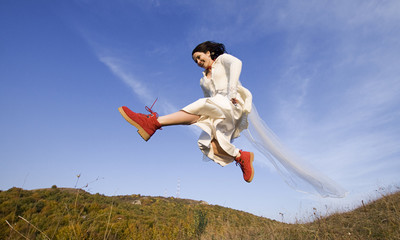 Romantic woman with red boots jumping on field