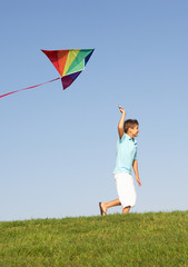 Young boy runs with kite through field