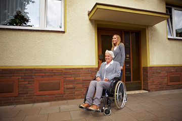 Rollstuhlfahrerin vor Haustür
