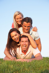 Two, young couples posing on a field