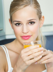 Portrait of young woman with orange juice, indoors