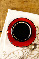 black coffee, red enamel mug, two old silver spoons on embroider