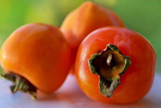 Frutas maduras do caqui em fundo verde.