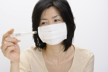 体温計を見つめる女性