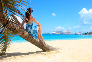 vrouw op een palmboom met uitzicht op cruiseschepen in de caribbean