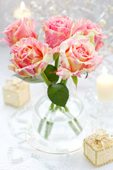 Bouquet of pink roses in vase,candles and little gift boxes