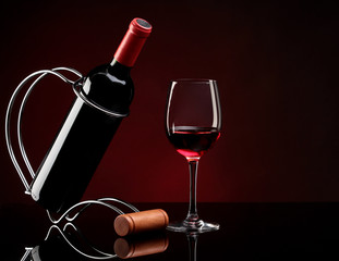 bottle with red wine on a stand and glass