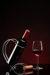 bottle with red wine on a stand and glass