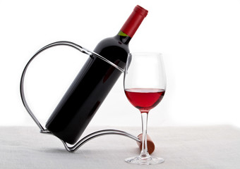 bottle with red wine on a stand and glass