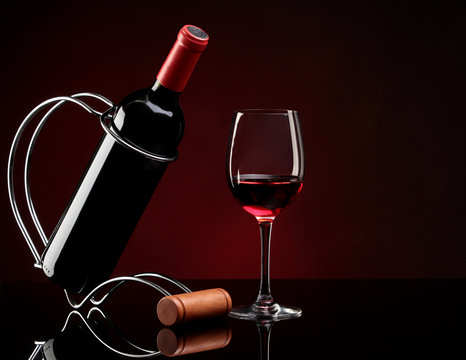 bottle with red wine on a stand and glass