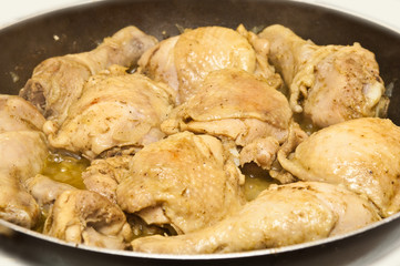 fried chicken cooking in pan against a white background