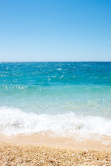 Fototapeta na wymiar beautiful pebbles beach with waves and blue sky