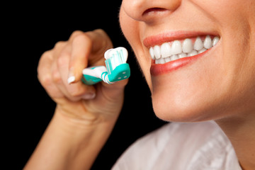 Woman healthy teeth closeup with toothbrush on black background