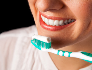 Woman healthy teeth closeup with toothbrush on black background