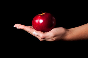 Woman holding red apple on black background