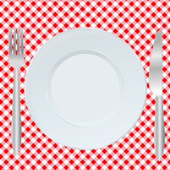 Plate, fork and spoon on red square tablecloth