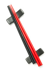 Red and black wodden chopsticks on holder over white