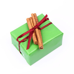 Gift in green wrapping with a red bow with cinnamon sticks