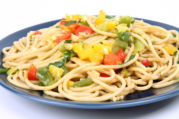 Spaghetti with vegetables on a plate in close up on white