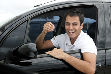 Happy hispanic man in his new car showing key