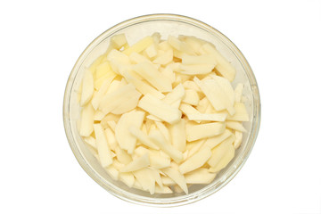Slices of uncooked potato in a glass bowl isolated on white