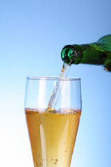 Someone fill glass with beer on blue background