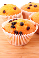 Muffins with raisins on wooden surface