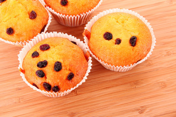 Muffins with raisins on wooden surface