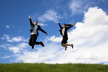 Fototapeta na wymiar Businessman and businesswoman jumping on a green meadow .