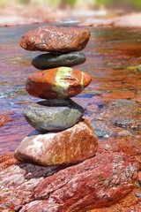Fototapeta na wymiar Rolling stones stacked red rodeno limestone in river