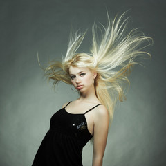 Fashion portrait of the young blonde woman with flying hair