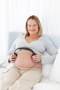 Future mom putting headphones on her belly