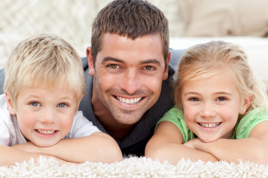 Children with father smilling to the camera in the carpet