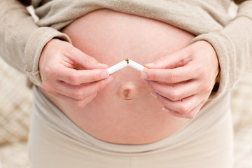 Close up of an attentive pregnant woman breaking a cigarette