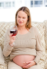 Obraz na płótnie Canvas Pregnant woman looking at a glass of red wine