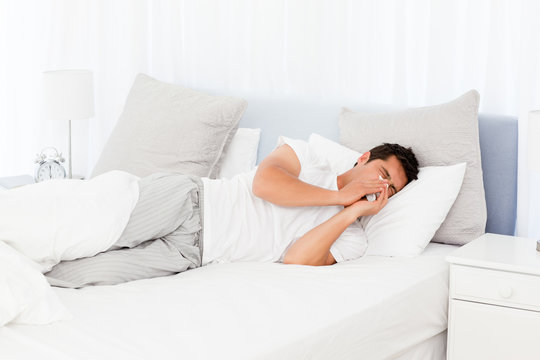 Sick Man Blowing His Nose Lying On His Bed