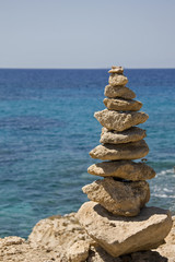 Fototapeta na wymiar Stones balanced on cliff over sea in the background