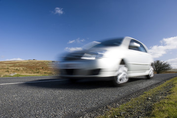 Naklejka premium Blurred silver car on mountain road